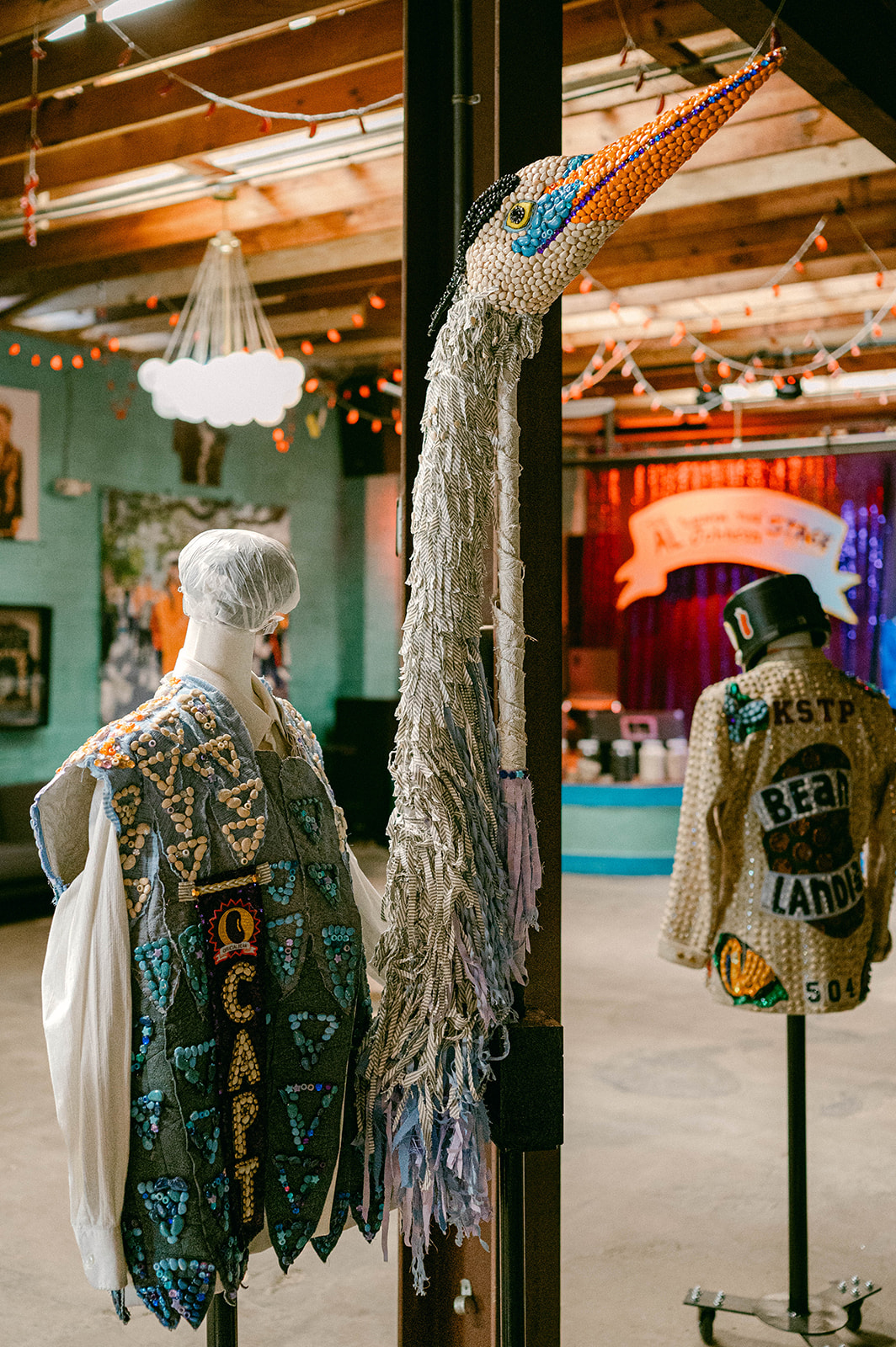 Inside Beanlandia — hand-beaned parade costumes on mannequins, pelican sculpture, and the main stage in the background