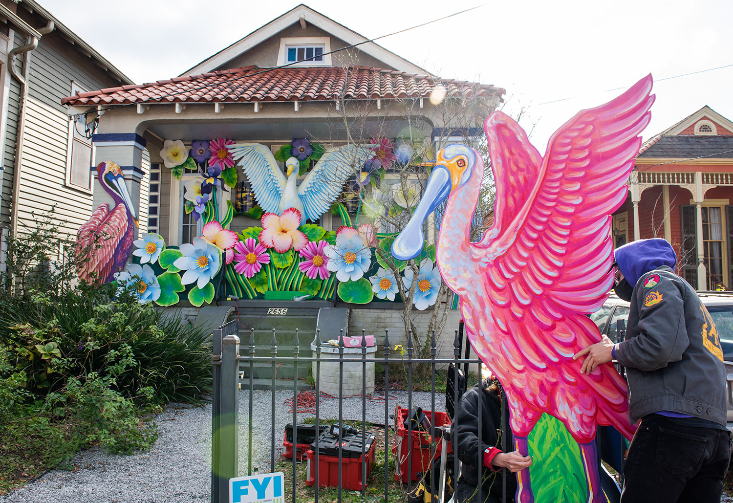 Artist carrying a large pink roseate spoonbill cutout while installing a house float